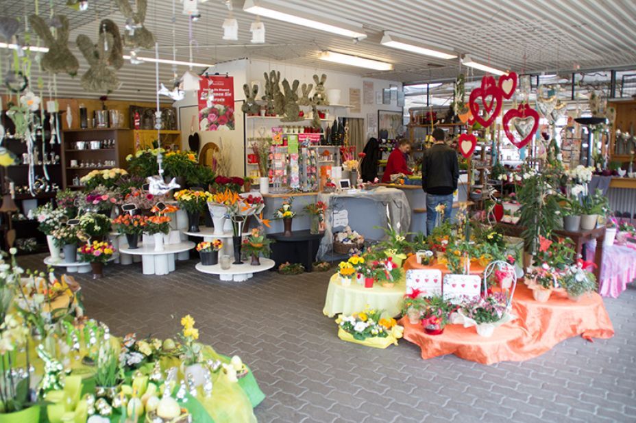 In einem Blumenladen werden auf den Tischen bunte Blumensträuße und Dekorationen präsentiert.