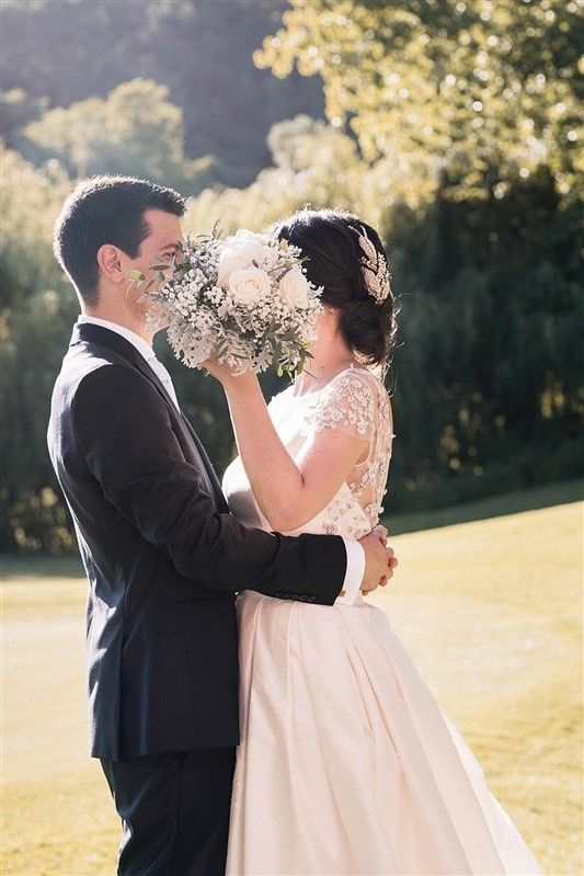 Uma noiva e um noivo estão de pé um ao lado do outro e a noiva está a segurar um bouquet de flores.