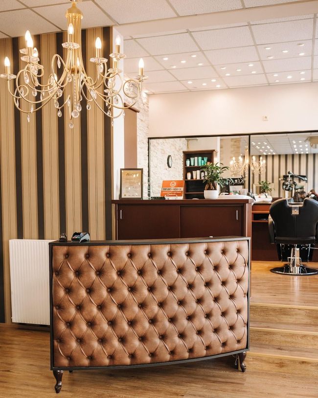 Empfangstresen in einem Salon mit brauner, gesteppter Front, Kronleuchter und einem Stuhl.