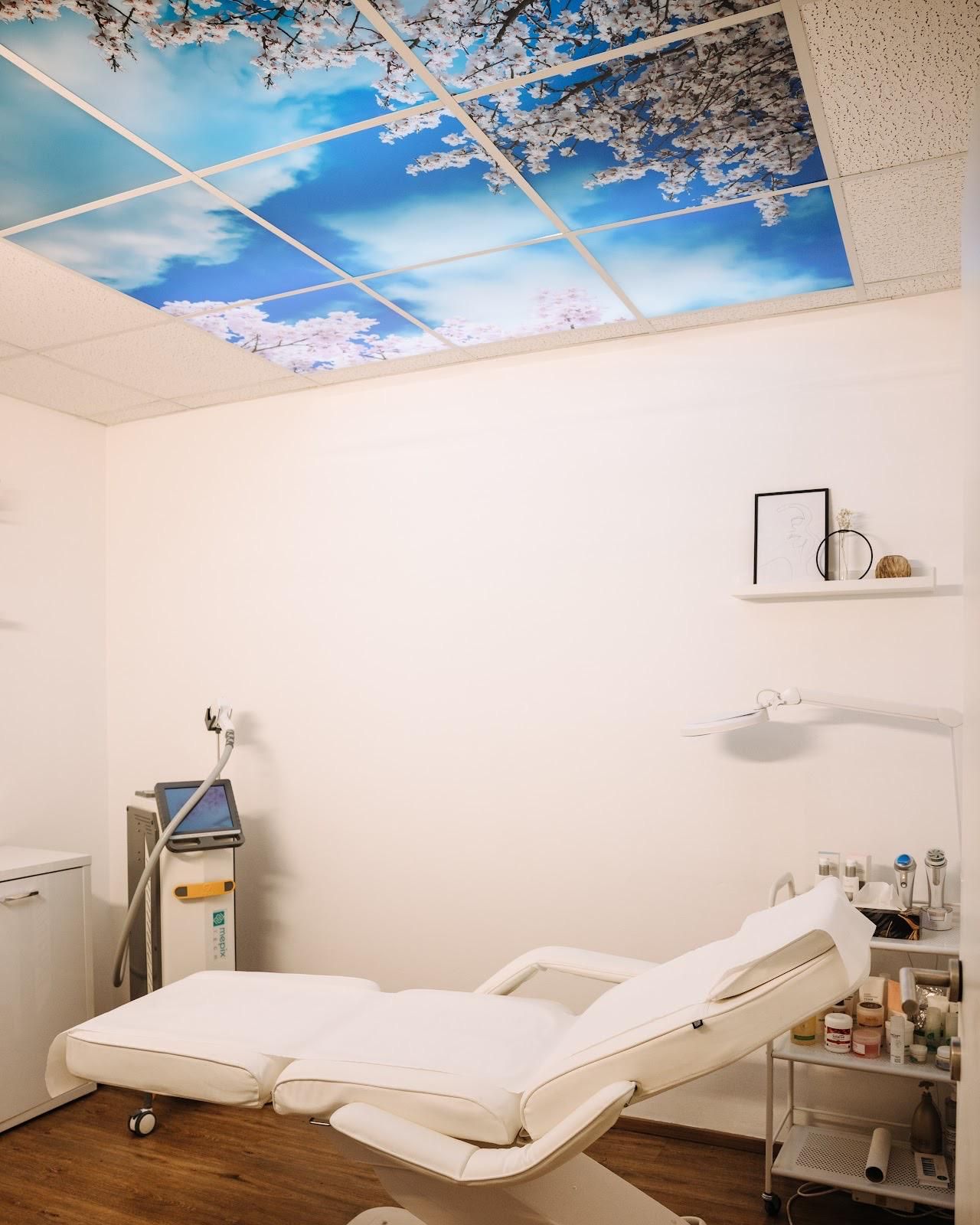 Spa-Behandlungsraum mit einem weißen, verstellbaren Stuhl und einem Deckengemälde mit Himmel und Kirschblüten.