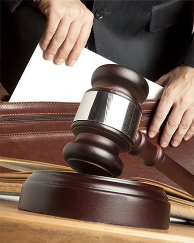 El mazo del juez golpea documentos legales con las manos en un entorno judicial.