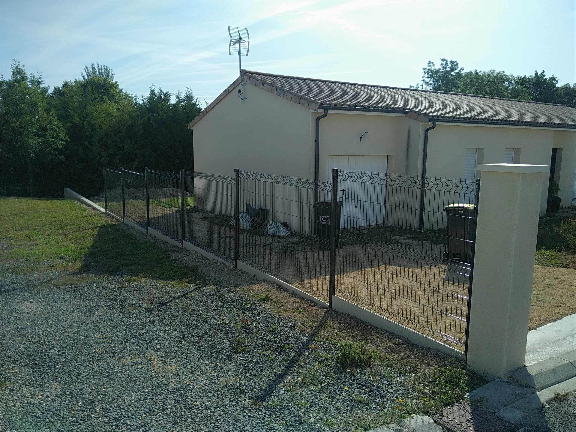 Une maison beige avec une clôture en métal noir devant, par une journée ensoleillée.