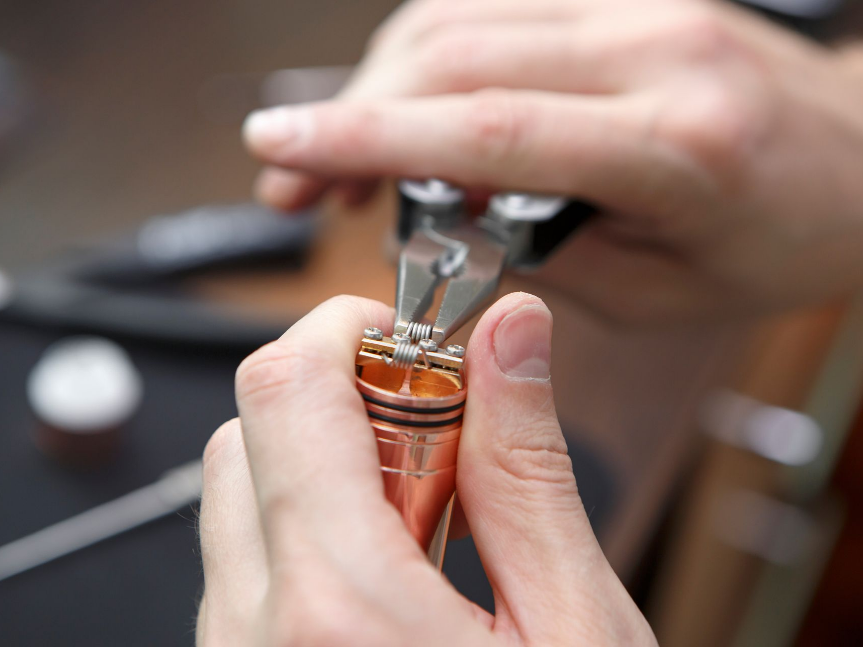 Mains utilisant des pinces pour assembler un appareil en cuivre.