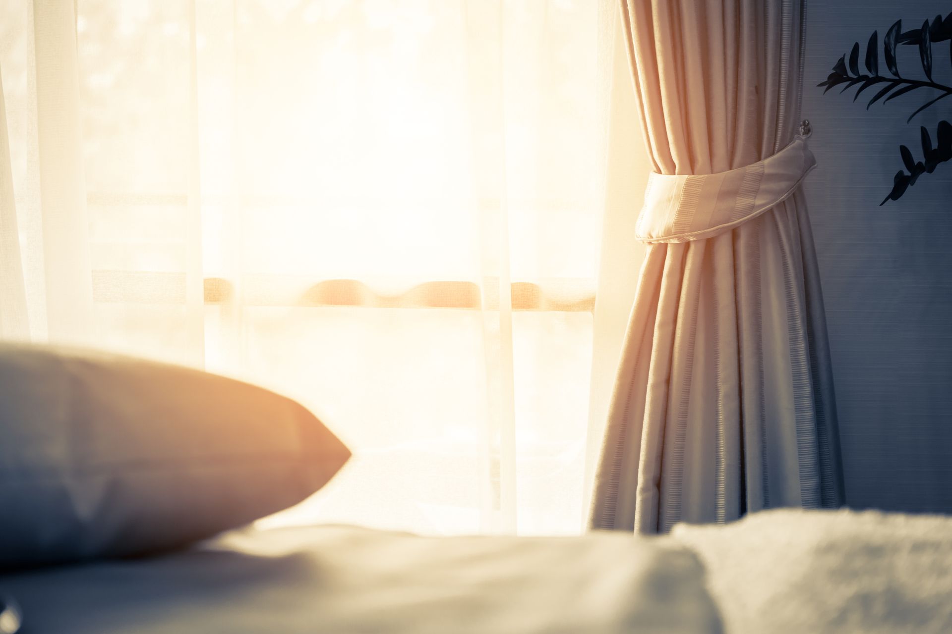 Fenêtre avec rideau et voilage, lit avec oreiller au premier plan