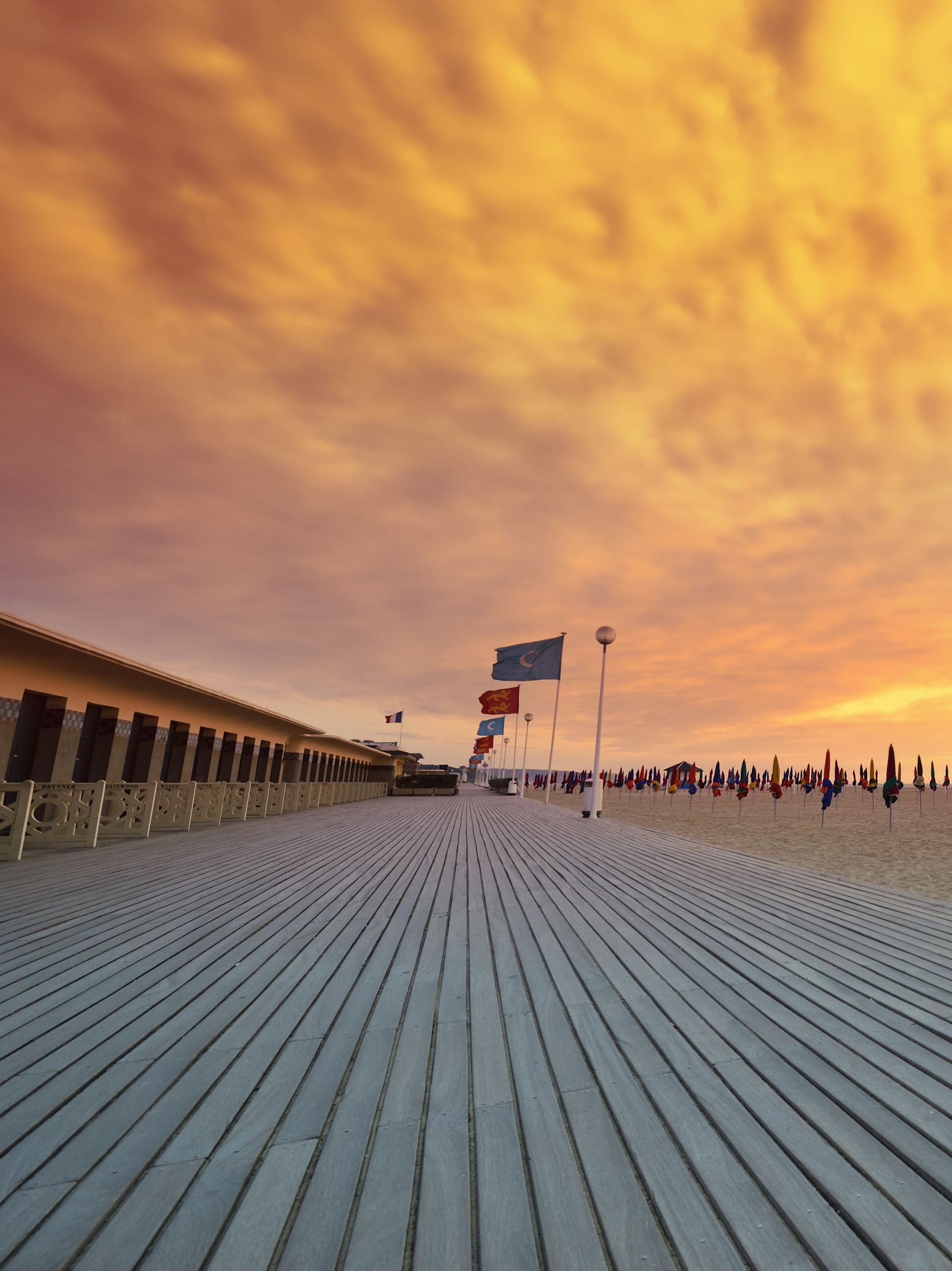 Plage de Deauville et ses planches, drapeaux et parasols plantés dans le sable