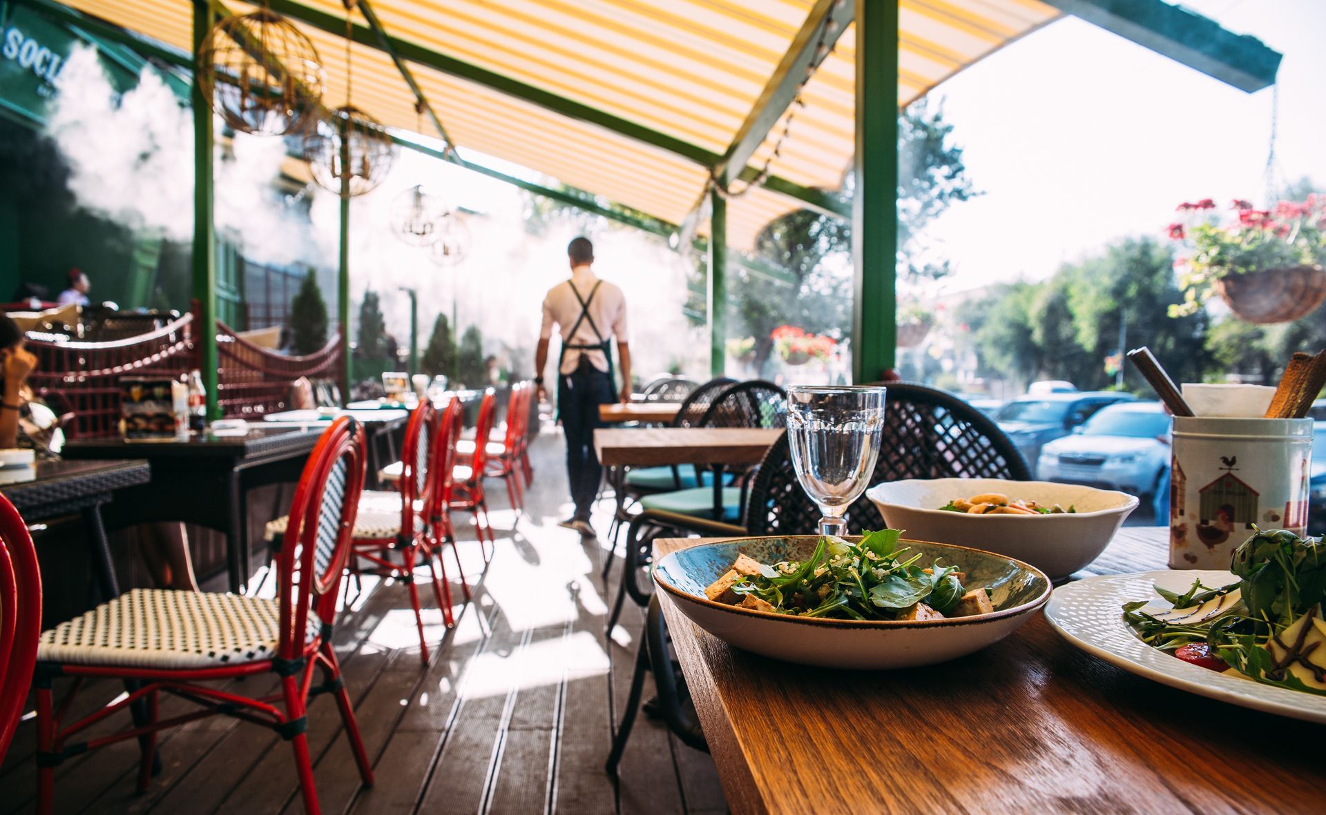 Terrasse d'un restaurant avec lames de bois, abritée sous un store banne