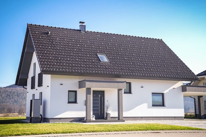 Ein weißes Haus mit einem braunen Dach und einer Veranda