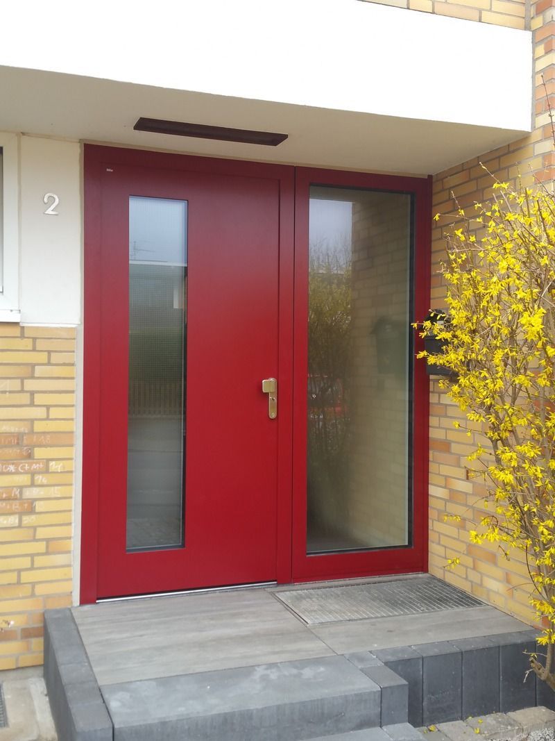 Die Eingangstür eines Backsteingebäudes mit einer roten Tür und Stufen.