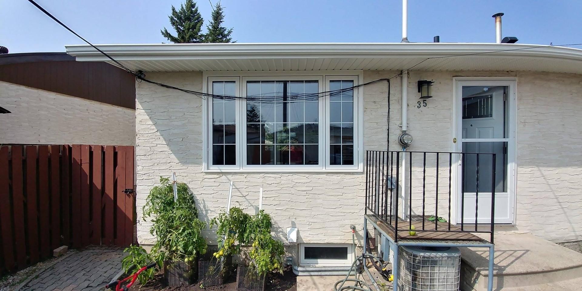 Ein weißes Backsteinhaus mit einem Balkon und Pflanzen davor