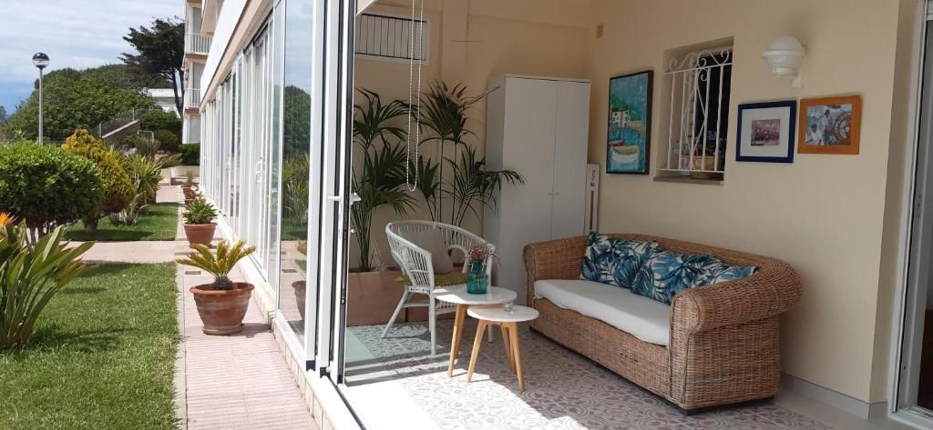 Patio cubierto con sofá de dos plazas de mimbre, puertas corredizas de vidrio y plantas.