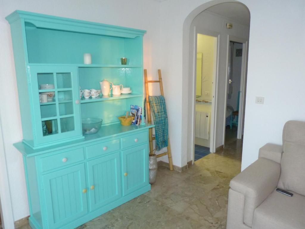 Vitrina turquesa en una sala de estar junto a una puerta arqueada y un sofá beige.