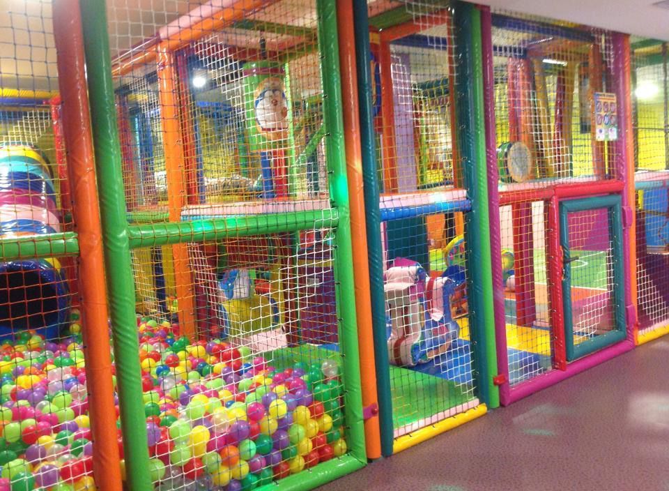 Área de juegos con redes de colores, piscina de pelotas y estructuras para escalar.