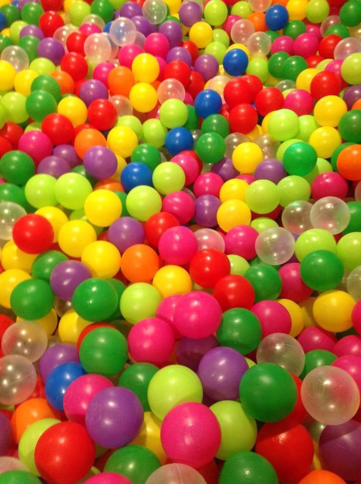 Bolas de plástico de colores llenan una piscina de bolas; una mezcla de bolas rojas, amarillas, verdes, azules, violetas, naranjas y transparentes.