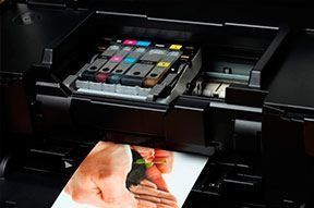 Impresora de inyección de tinta con cartuchos de tinta de colores que imprime una fotografía.