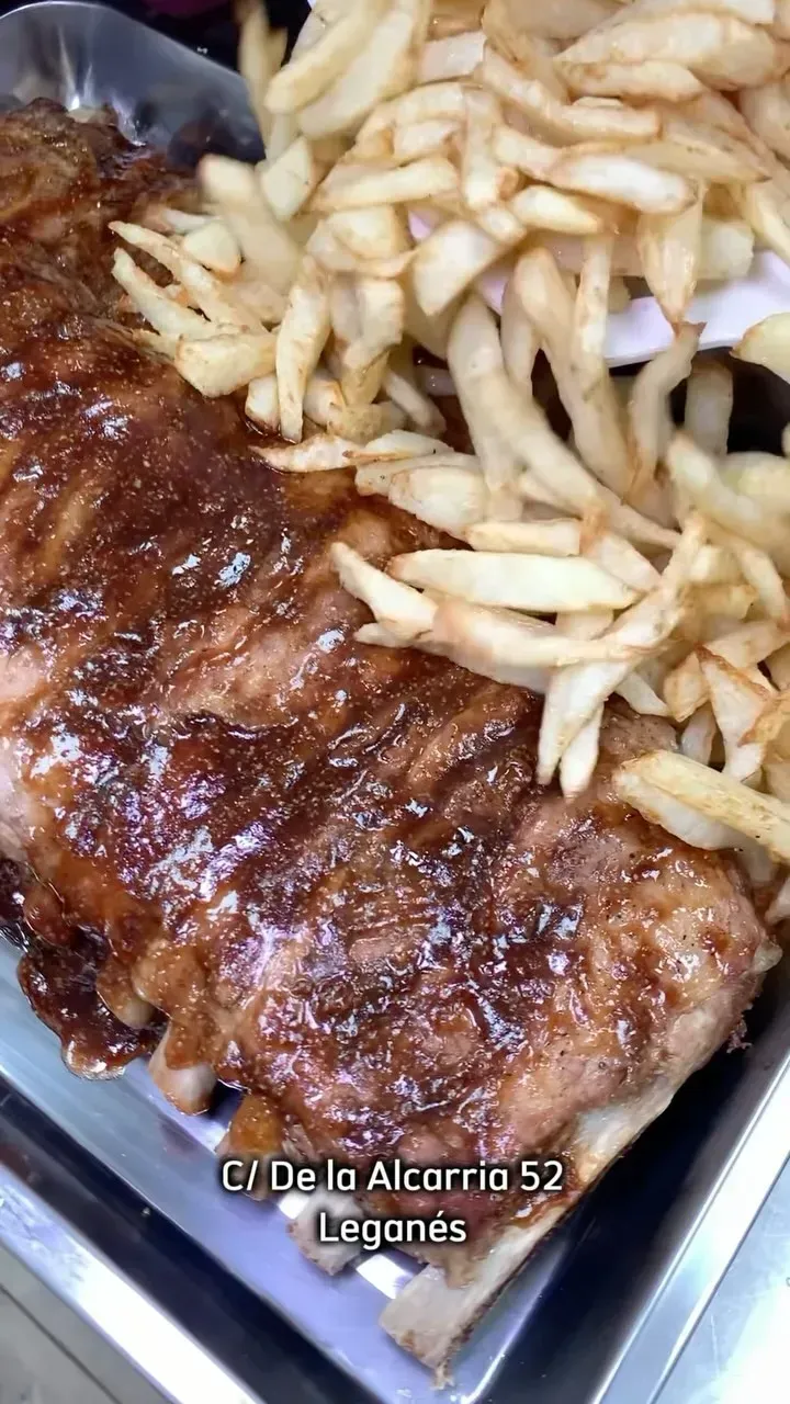 Un primer plano de costillas y papas fritas en una bandeja.