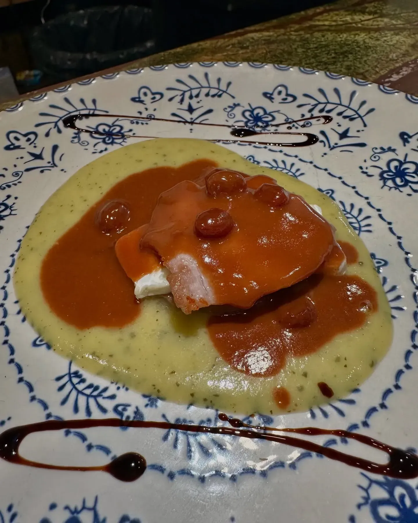 Un plato de comida con salsa y puré de papas en una mesa.