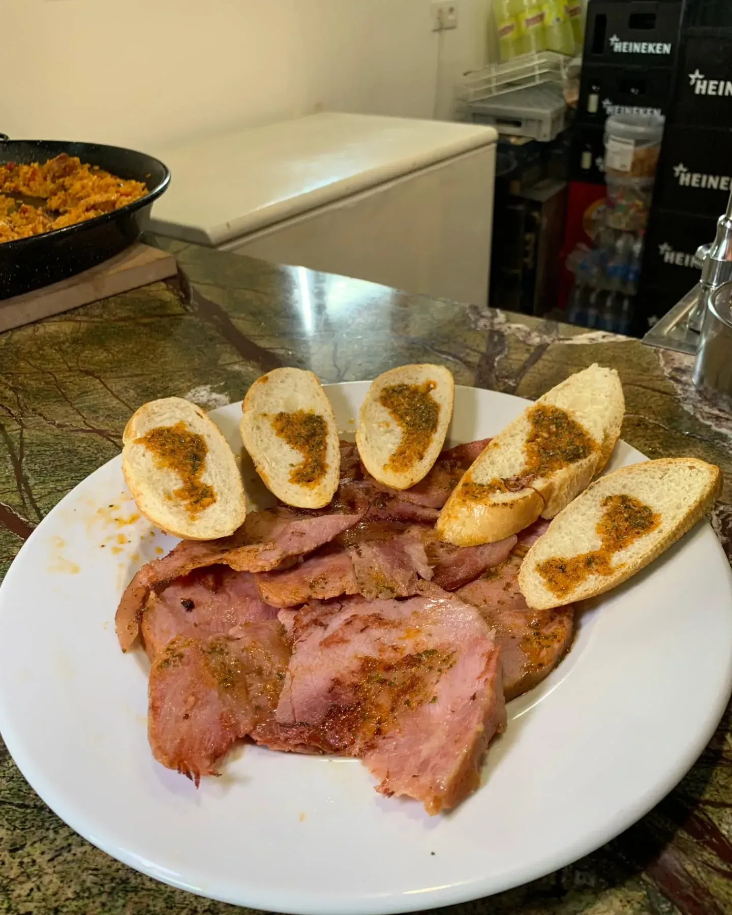 Un plato blanco cubierto con carne y pan sobre una mesa.