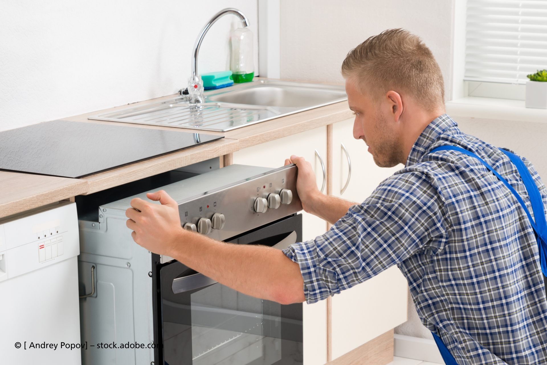 Elektrogeräte Nürnberger - Mann im Blaumann steht in einer Küche und erstellt Notizen