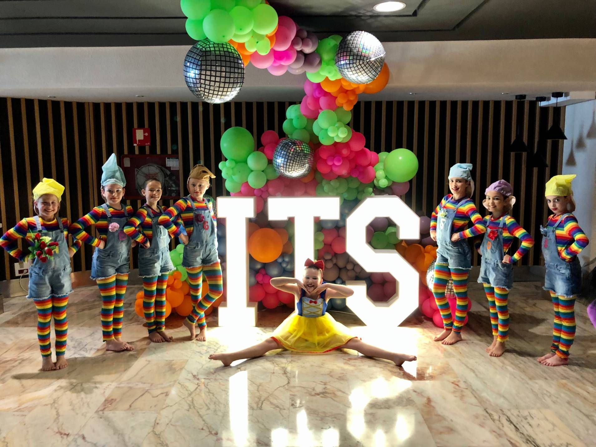 A group of children are standing in front of a sign that says `` it 's ''.