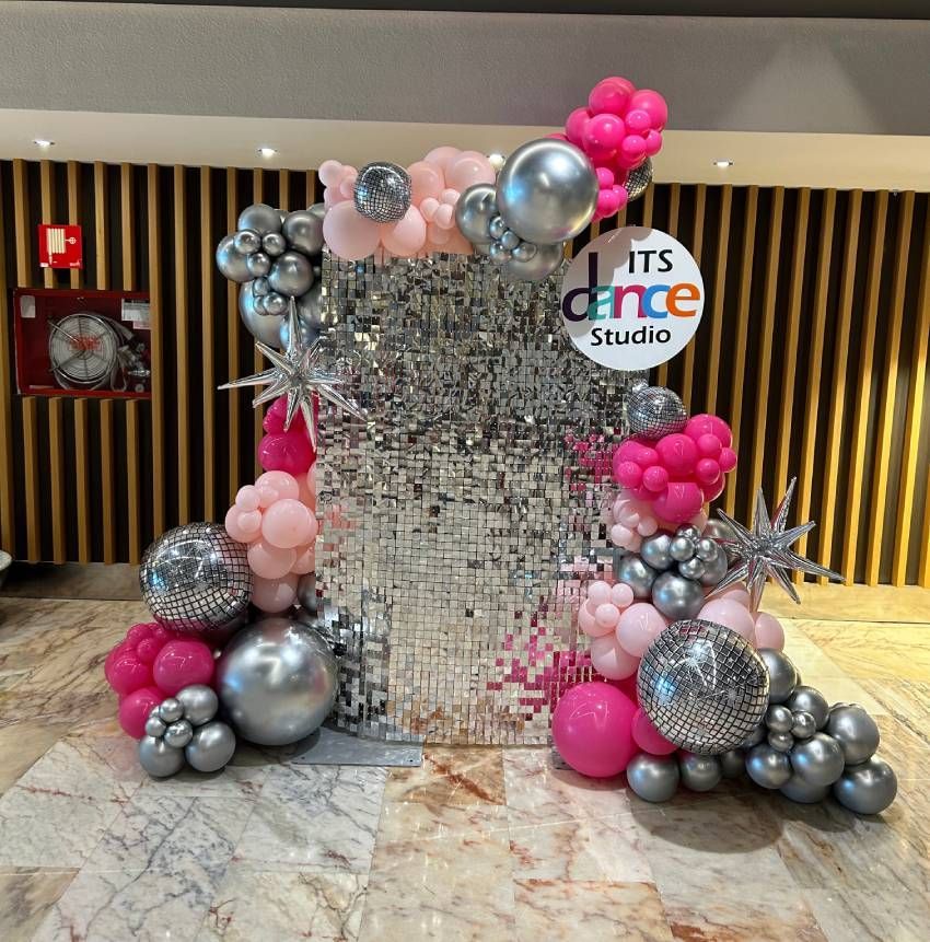A wall decorated with pink and silver balloons and a sign that says it 's dance studio.