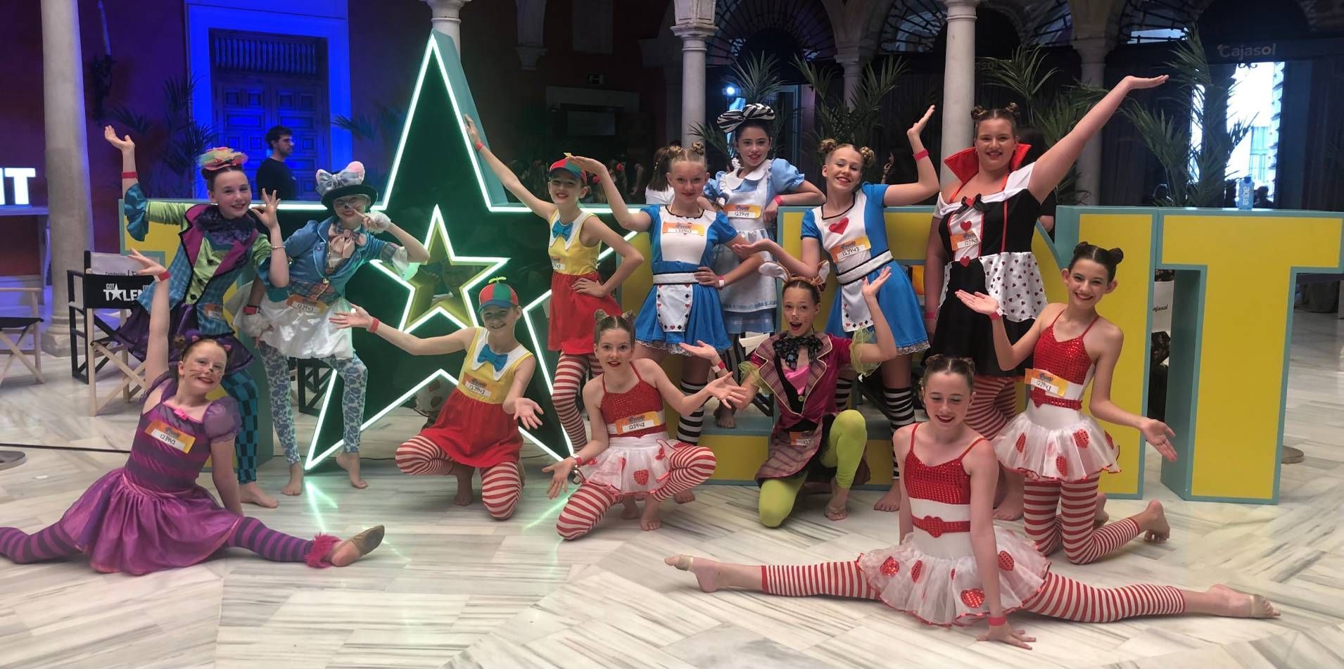 A group of young girls are posing for a picture in front of a christmas tree.