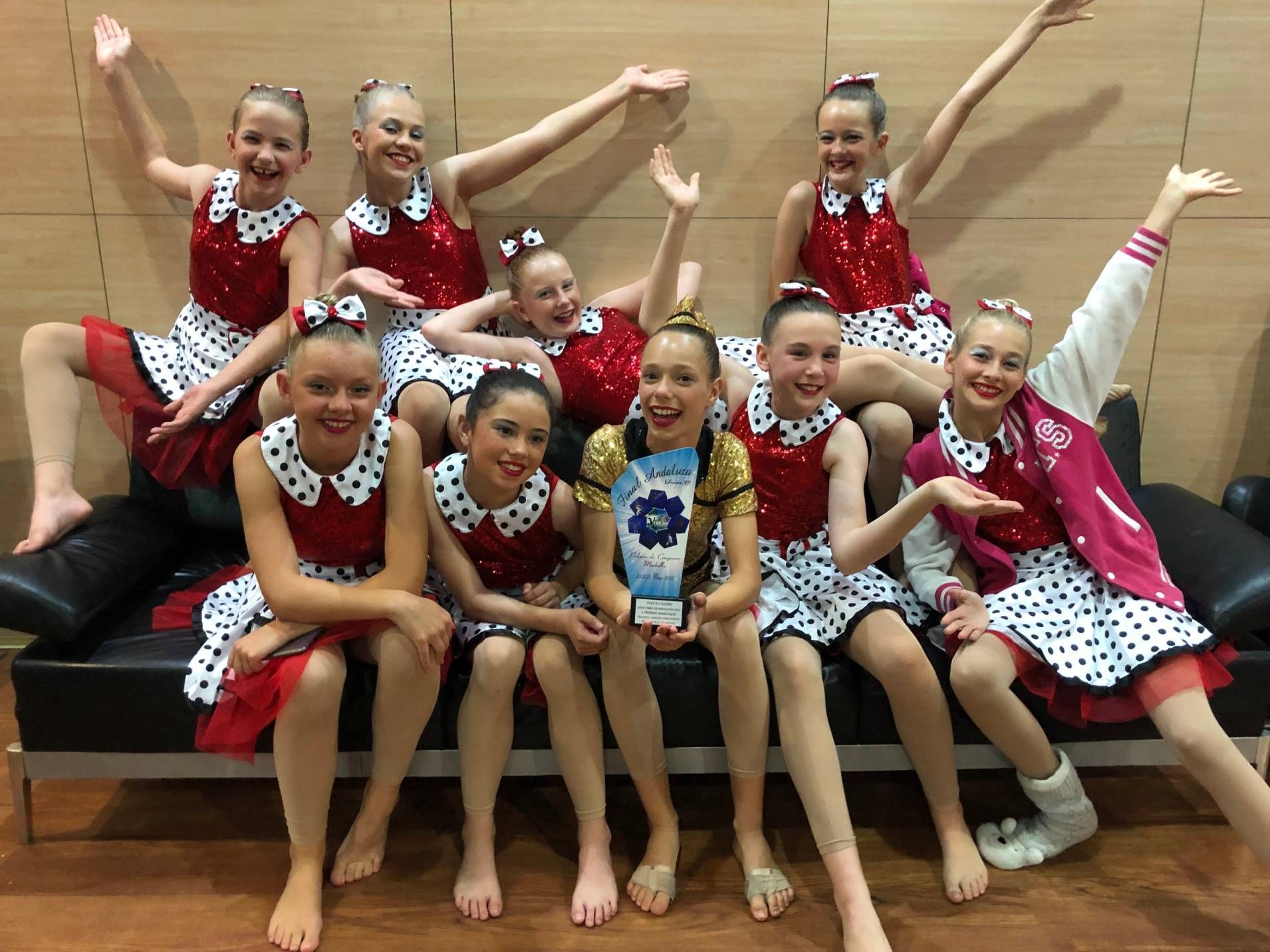 A group of young girls are posing for a picture while sitting on a couch.