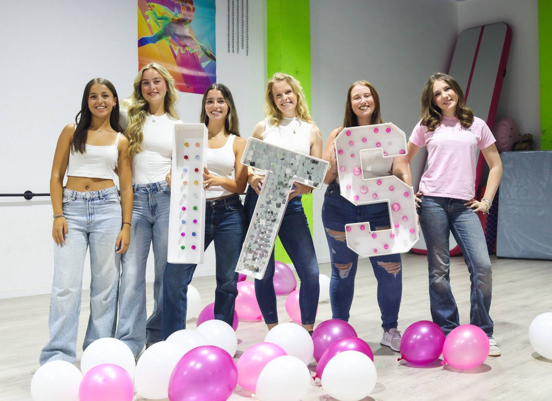 A group of women are standing next to each other holding giant letters and balloons.