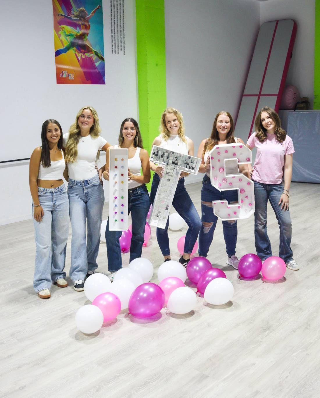 A group of women are posing for a picture with balloons and a sign that says ts.