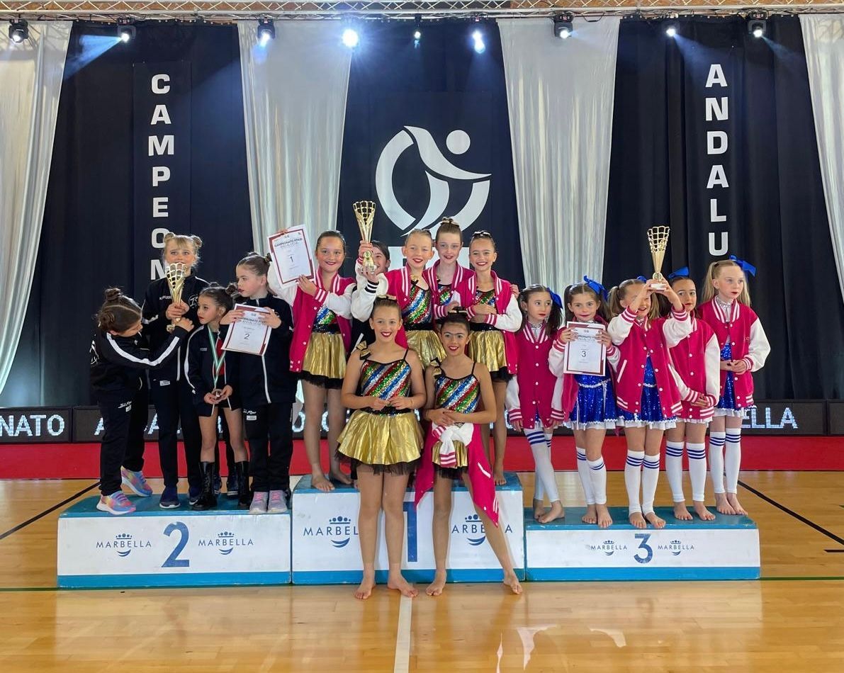 A group of young girls are standing on a podium holding trophies.
