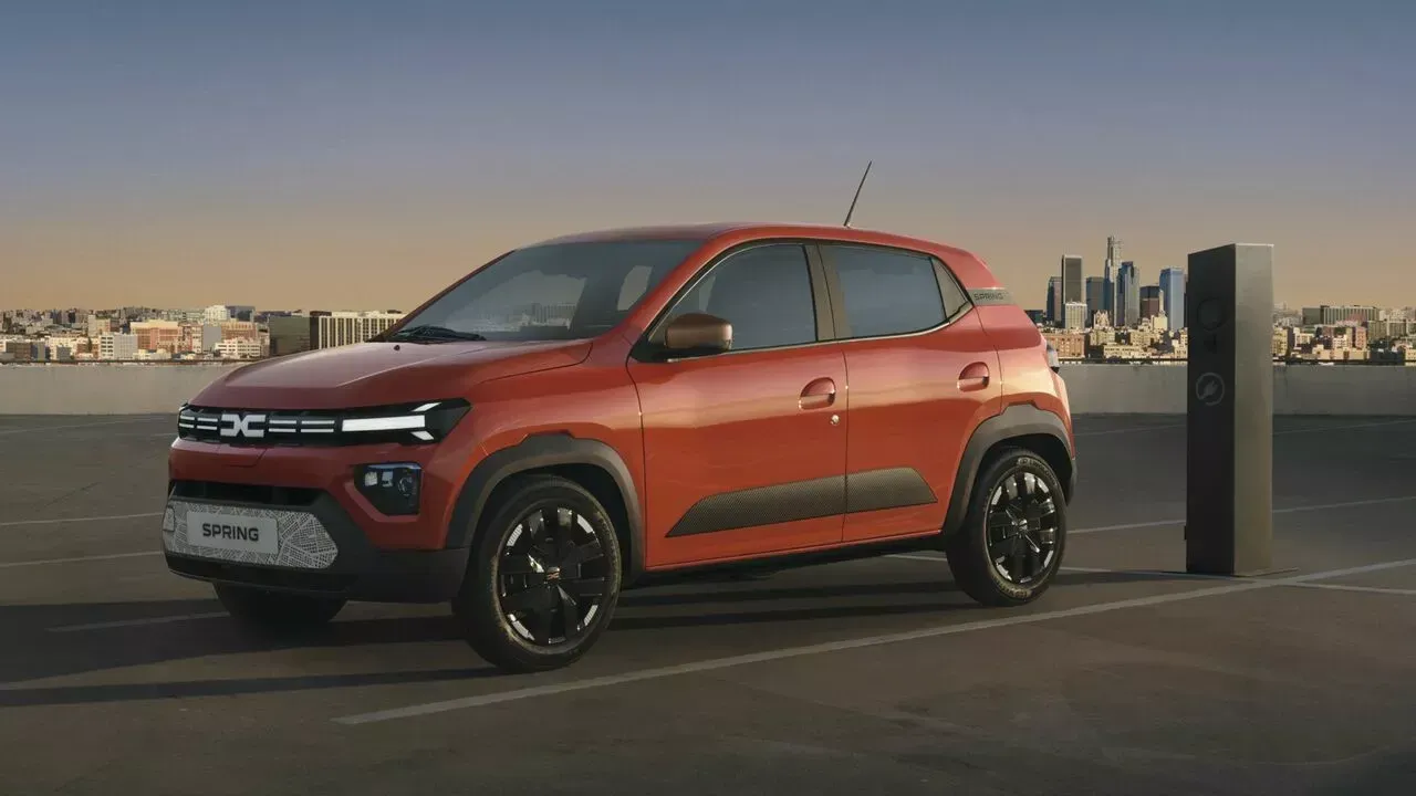 Devant d'un véhicule Dacia rouge avec une ville derrière