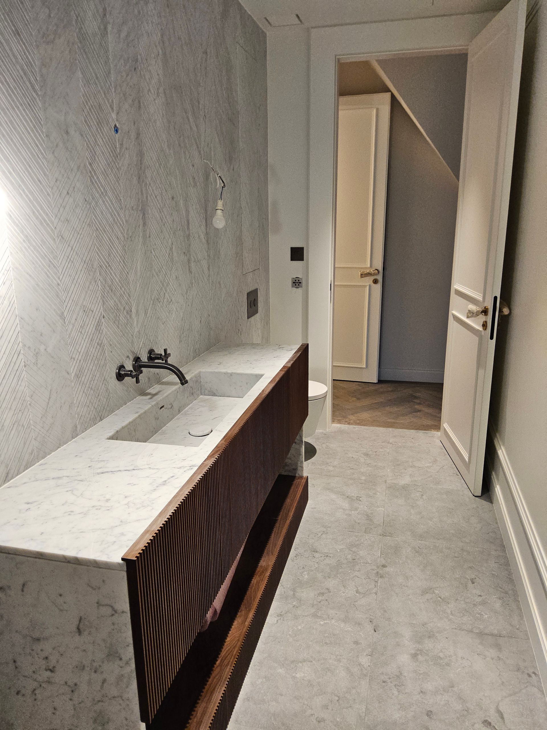 Une salle de bain avec un lavabo et une porte donnant sur un escalier.