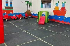 Una cocina con sillas y tronas rojas para niños, una mesa roja y una nevera decorada con personajes de dibujos animados.