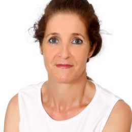 Mujer con cabello castaño rojizo, con un top blanco, mirando a la cámara.