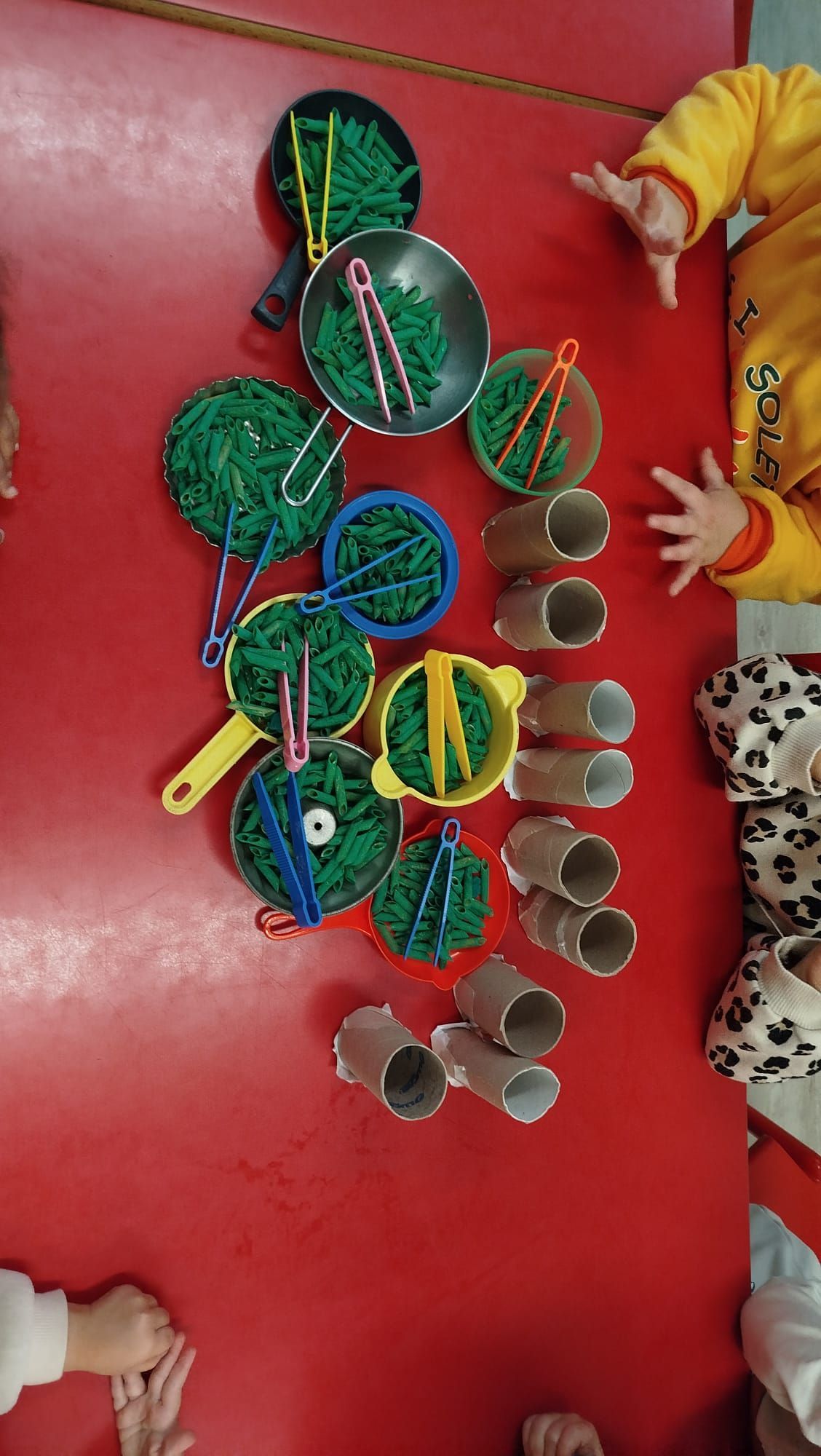 Tres niños pequeños construyen con bloques de colores en una mesa blanca.