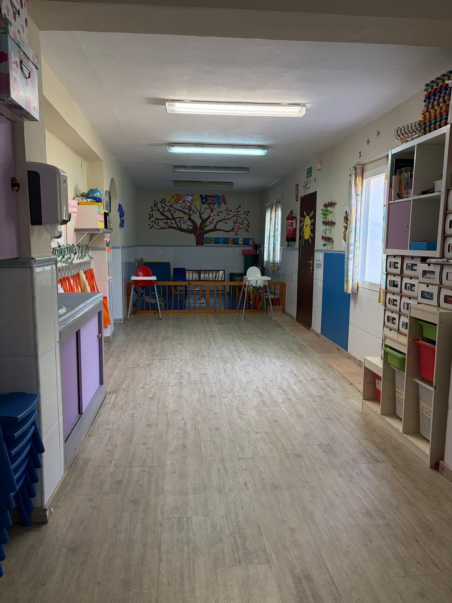 Una cocina con sillas y tronas rojas para niños, una mesa roja y una nevera decorada con personajes de dibujos animados.