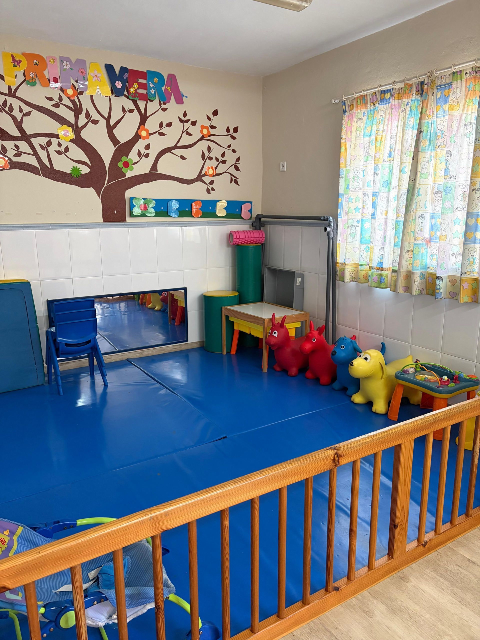 Aula vacía con arte de árbol, valla de madera, mesa y decoraciones.