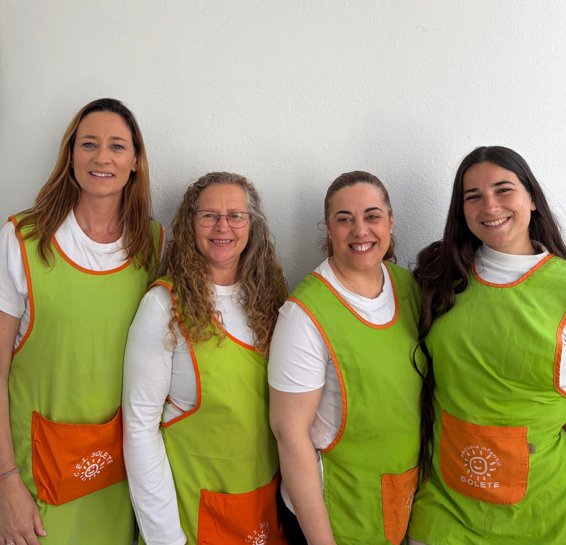 Cuatro personas disfrazadas y con máscaras: una mujer con corbata verde y falda de lentejuelas rojas, otras con corbatas y faldas de tutú.