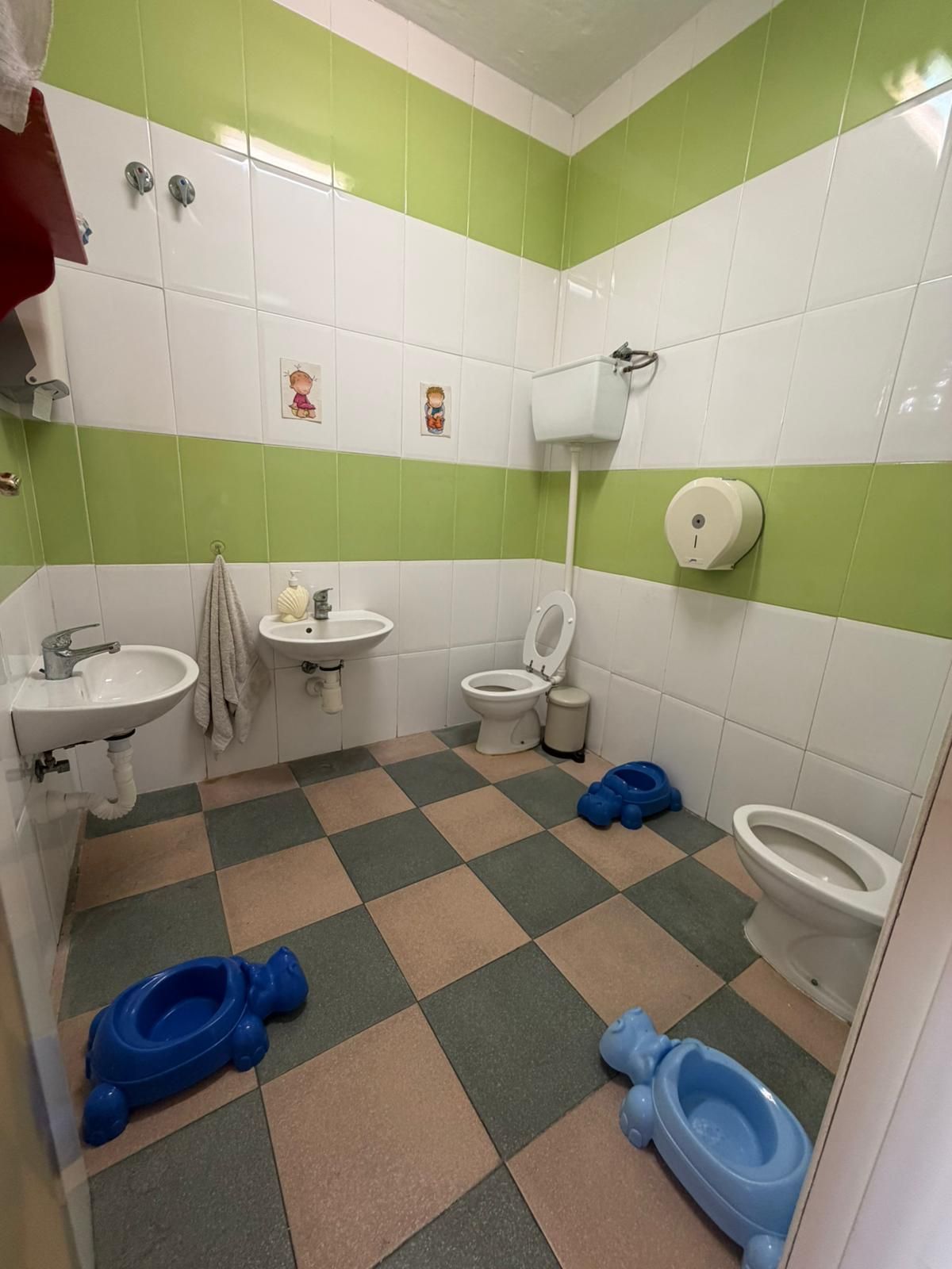 Una cocina con sillas y tronas rojas para niños, una mesa roja y una nevera decorada con personajes de dibujos animados.