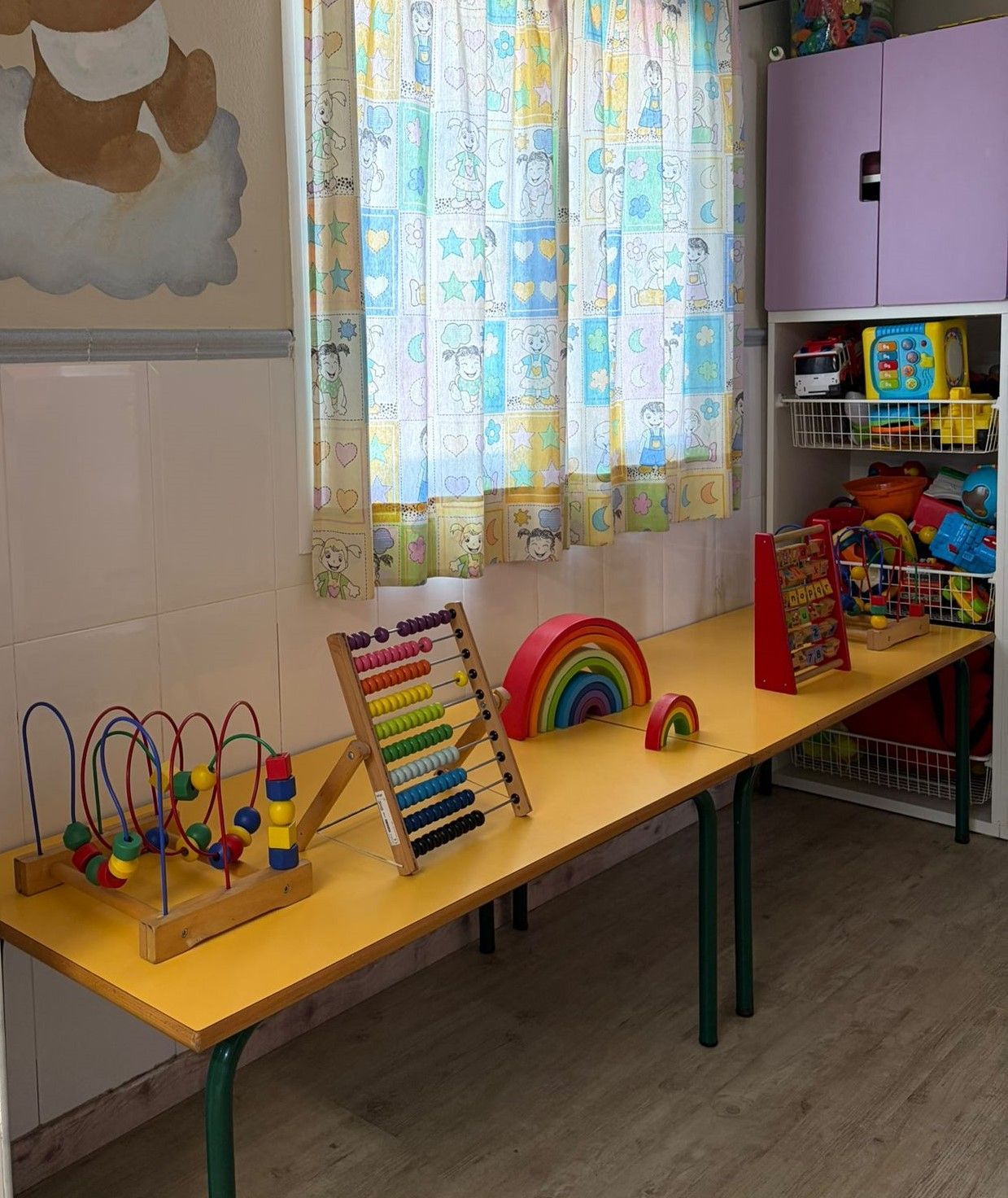 Un niño pequeño y su cuidador juegan con bloques de colores en una mesa en una sala de juegos de colores brillantes.