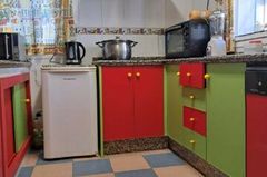 Una cocina con sillas y tronas rojas para niños, una mesa roja y una nevera decorada con personajes de dibujos animados.