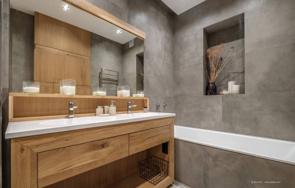 Badezimmer mit Holzwaschtisch, grauen Wänden, eingebautem Regal mit Dekor und einer Badewanne.