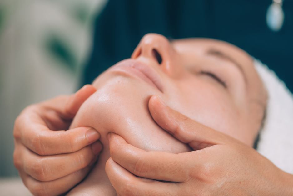 Persona recibiendo un masaje con piedras calientes en la espalda, manos colocando las piedras.