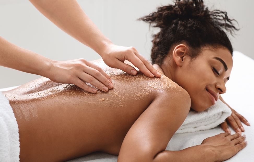 Persona recibiendo un masaje con piedras calientes en la espalda, manos colocando las piedras.
