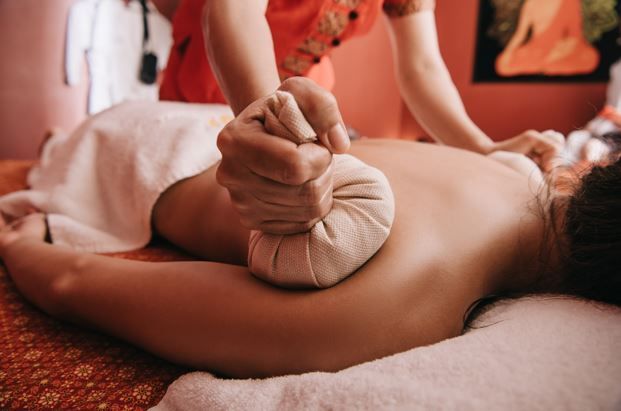 Persona recibiendo un masaje de espalda con compresas de hierbas.