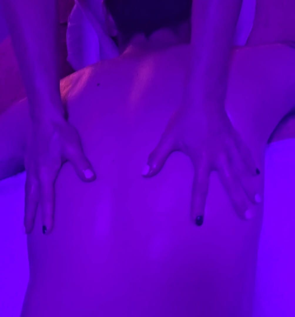 Manos presionando una espalda bajo iluminación violeta