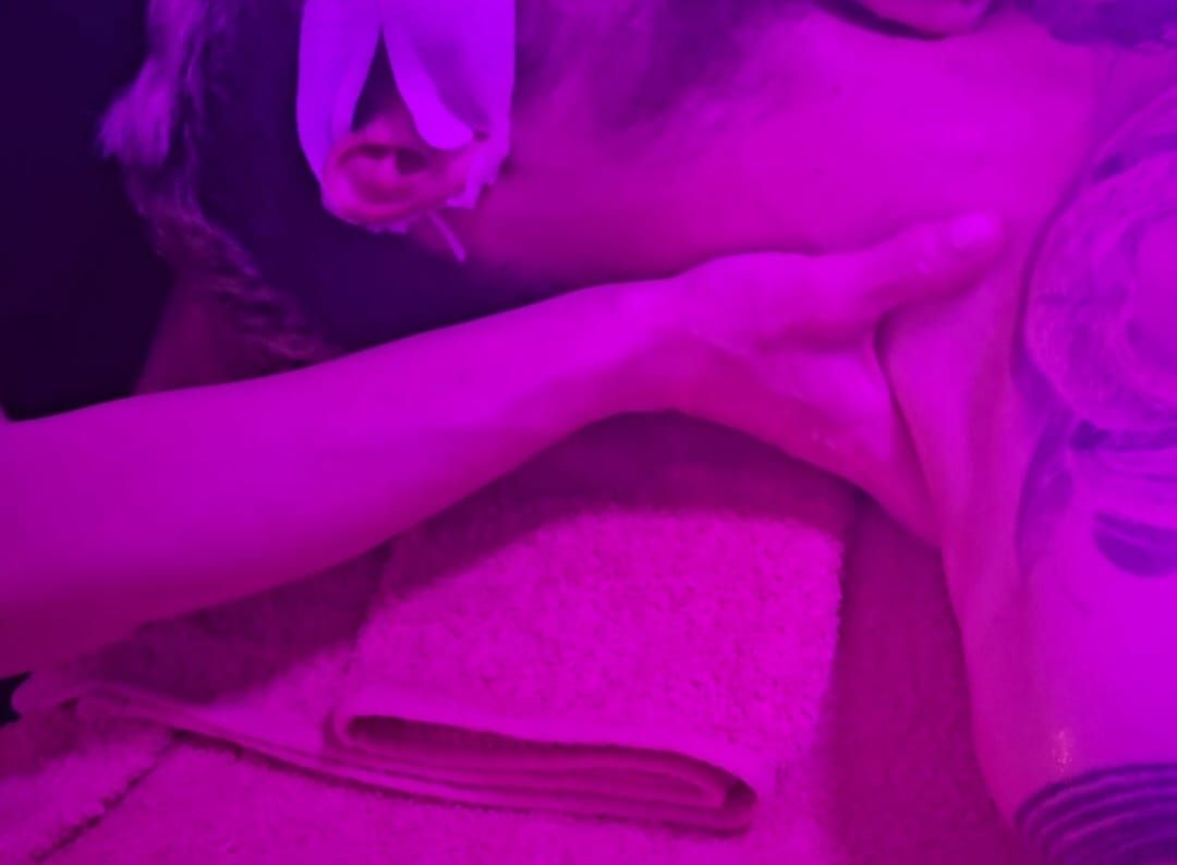 Una persona descansa en un sofá bajo una luz violeta, con una mano en la cara y una manta cerca.