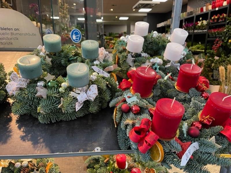Eine Ausstellung von Weihnachtskränzen mit Kerzen in einem Geschäft