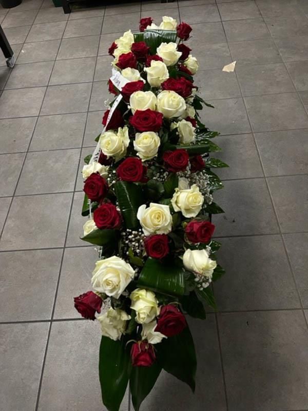 Ein langes Arrangement aus roten und weißen Rosen auf einem gefliesten Boden