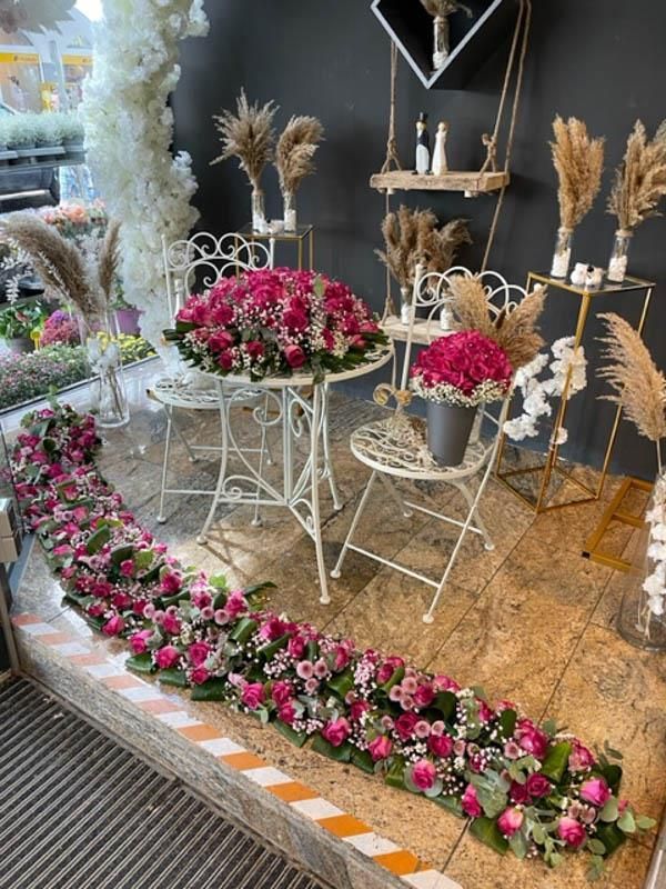 Ein Raum voller rosa Blumen auf Tischen und Stühlen.