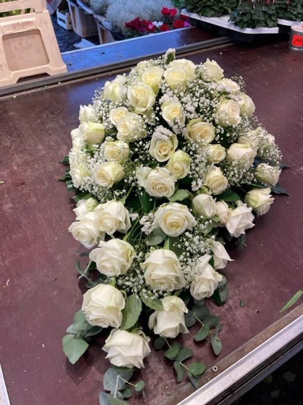 Ein Strauß weißer Rosen steht auf einem Holztisch.